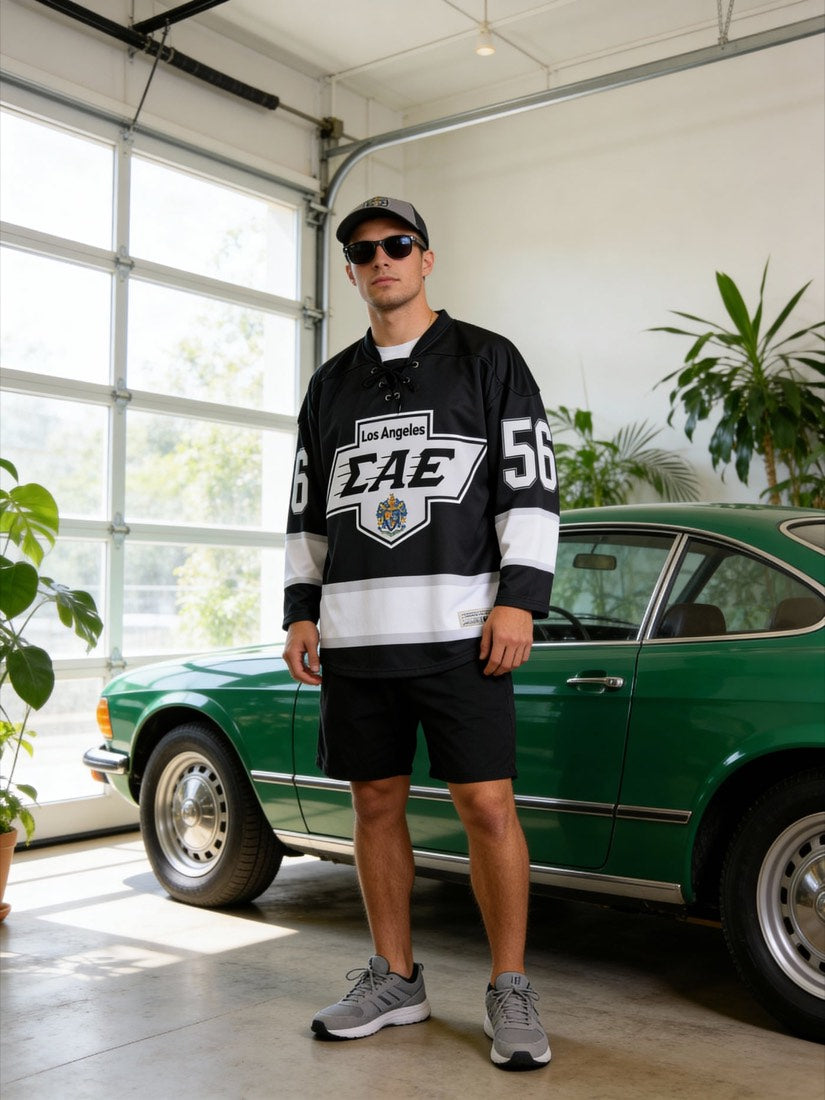 Man in a custom hockey-style jersey standing in a garage beside a green classic car